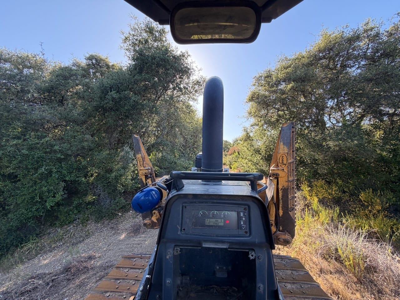 The view from the seat of a dozer cutting a trail through oak trees